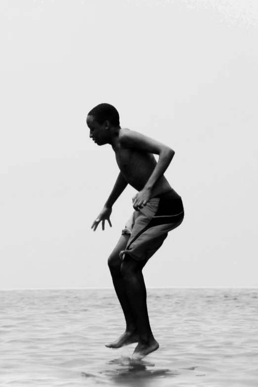 a shirtless man standing on top of the ocean while holding his hand