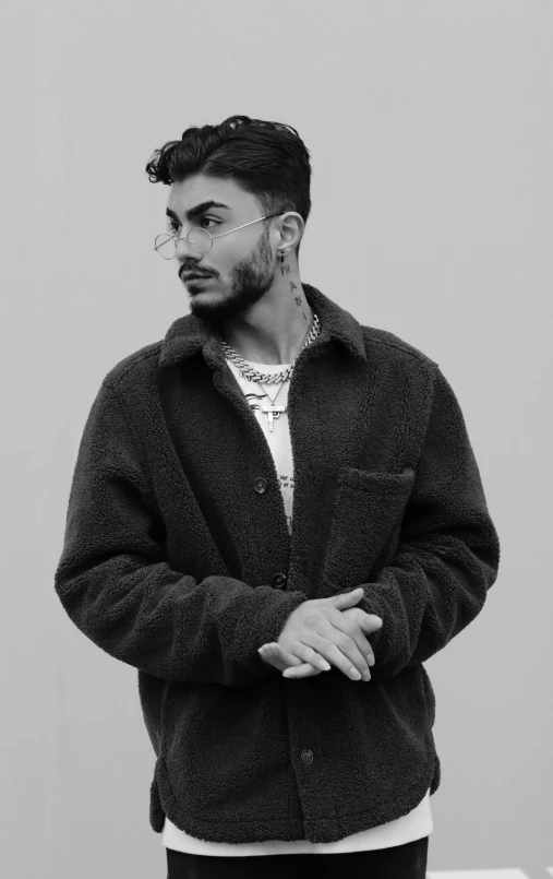 a man wearing a long sleeved jacket and standing with his arms crossed