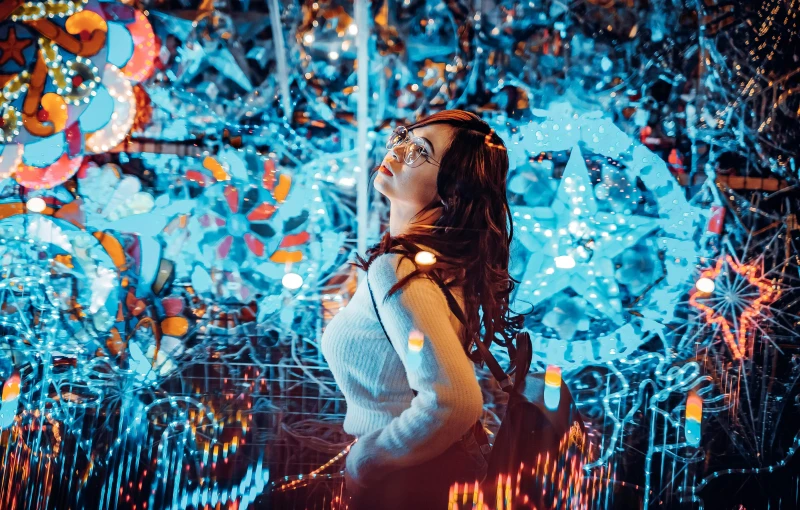 a woman looking up at an artwork made with string lights