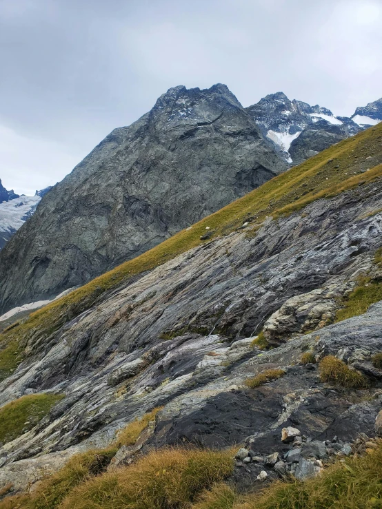 a hill with grass and rocks and snow on top