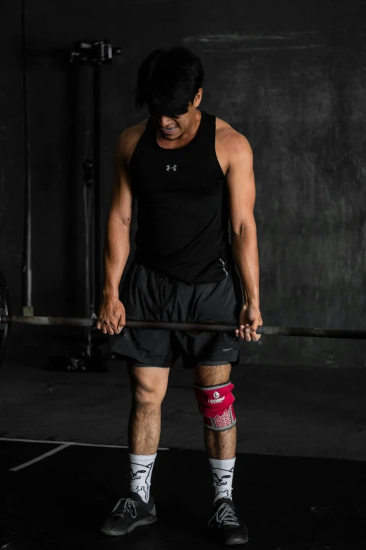 a man in black shirt holding up bar with red knee pads