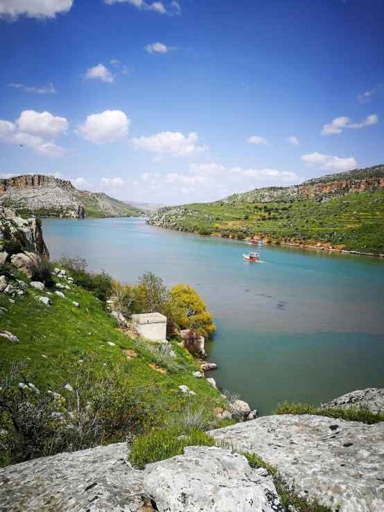 a lake surrounded by mountains is pictured from the hill top