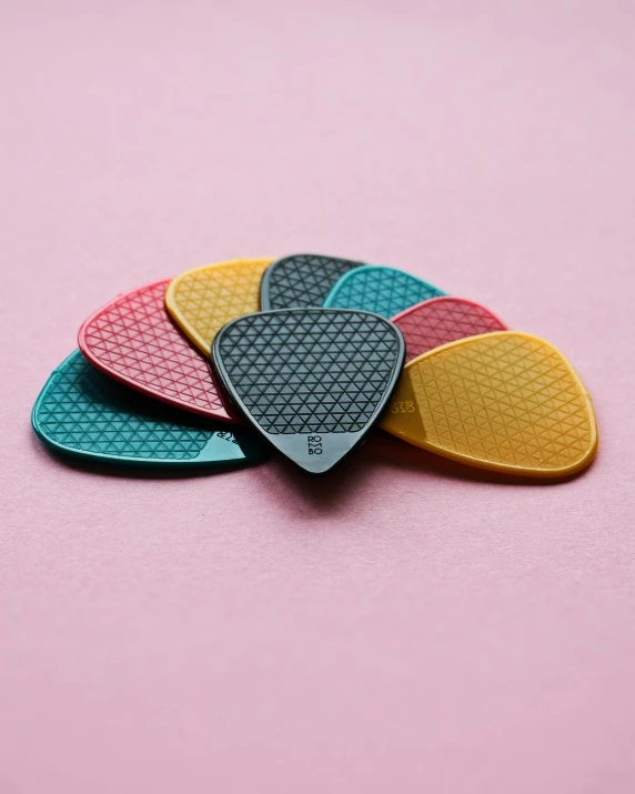 four picks of different colors on a pink surface