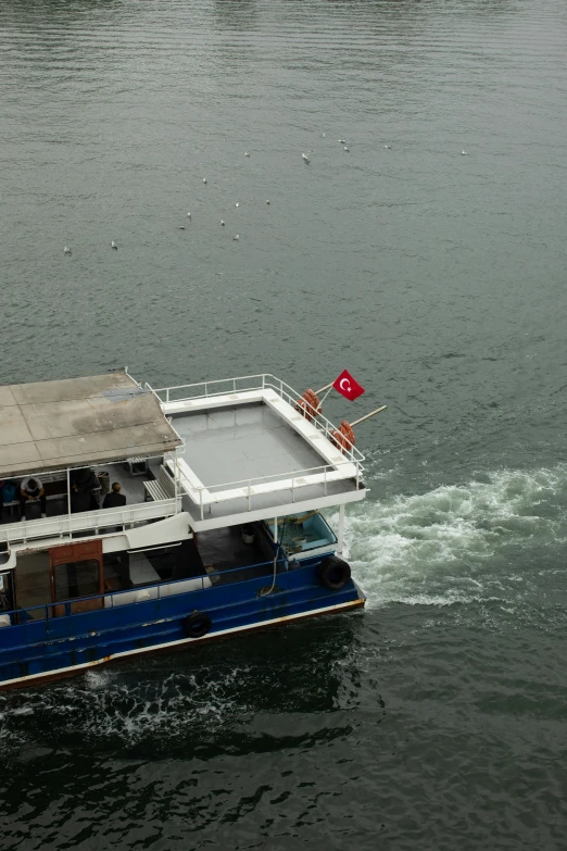 a boat with a red flag on top traveling across a body of water