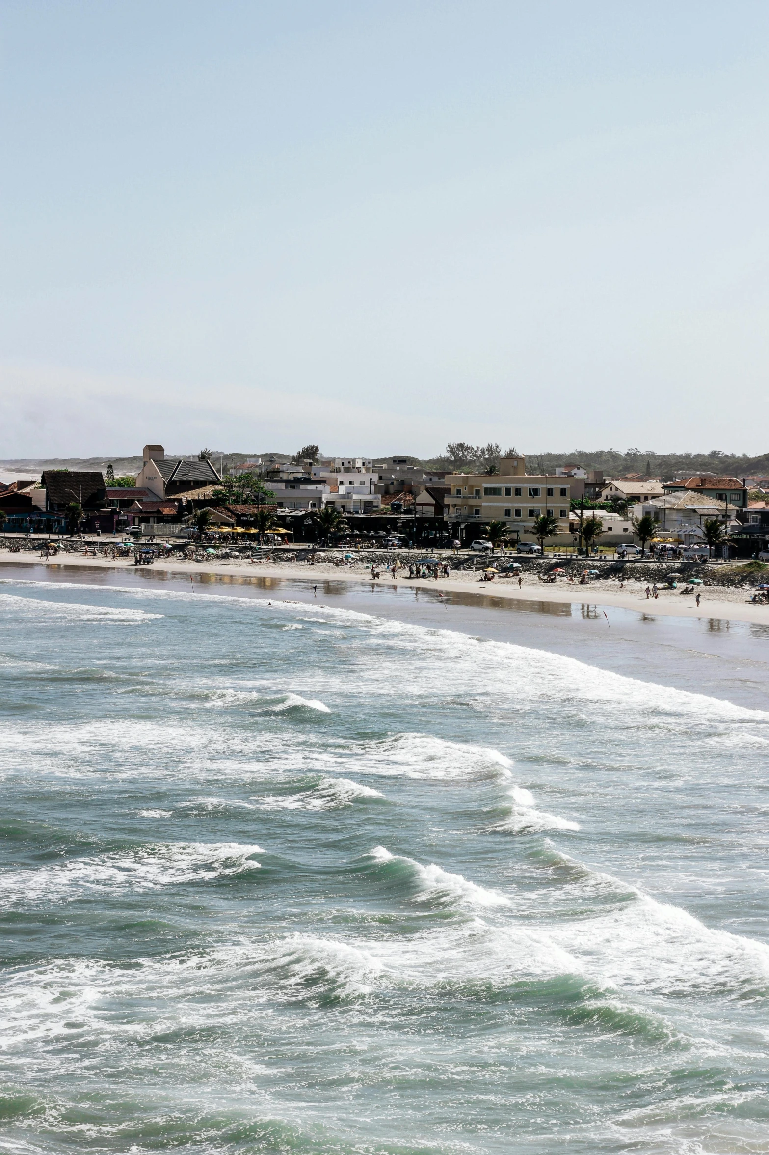 an ocean with white waves near a city beach