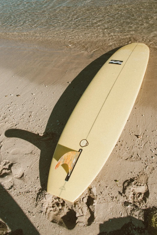 a surfboard rests on the sand next to the ocean