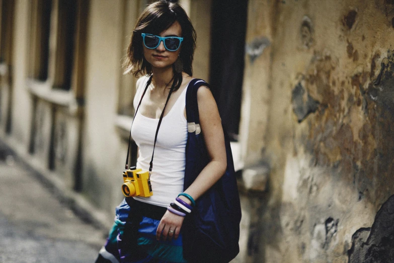 woman in blue sunglasses and a white shirt walking on the side of a road