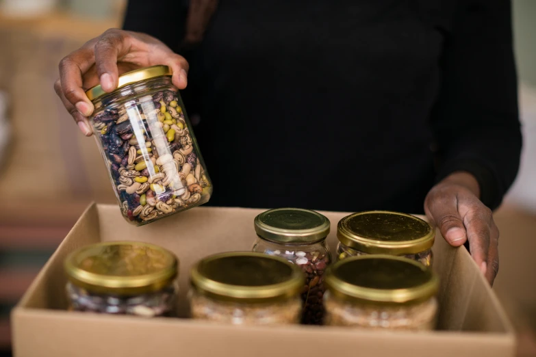 a person holding a can with nuts and grains inside