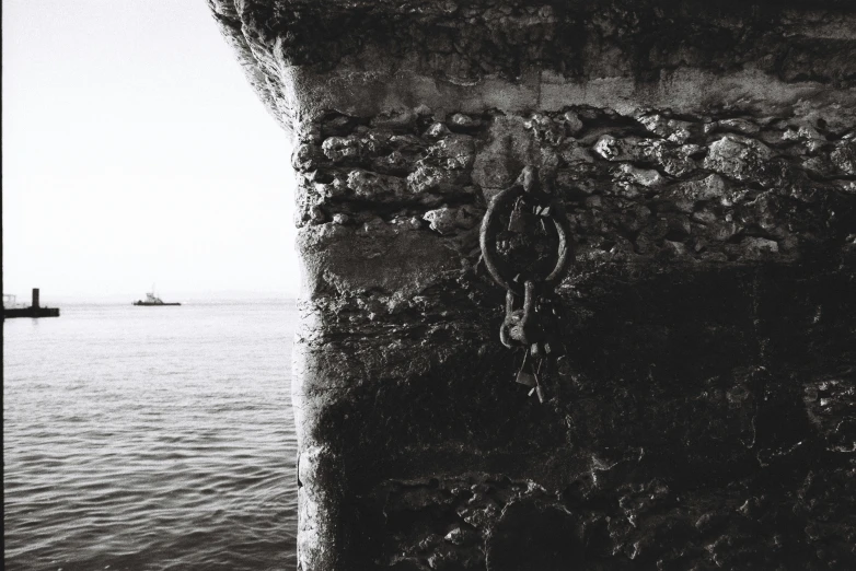 an iron hook on a stone wall by a sea
