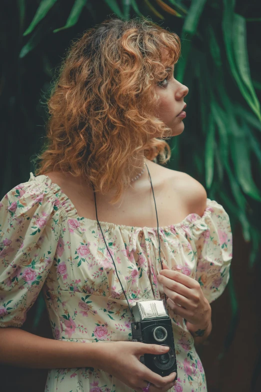 a woman holding an old camera looking ahead