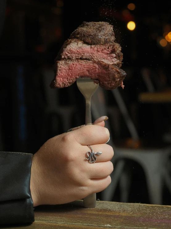 someone is holding up a steak on a fork