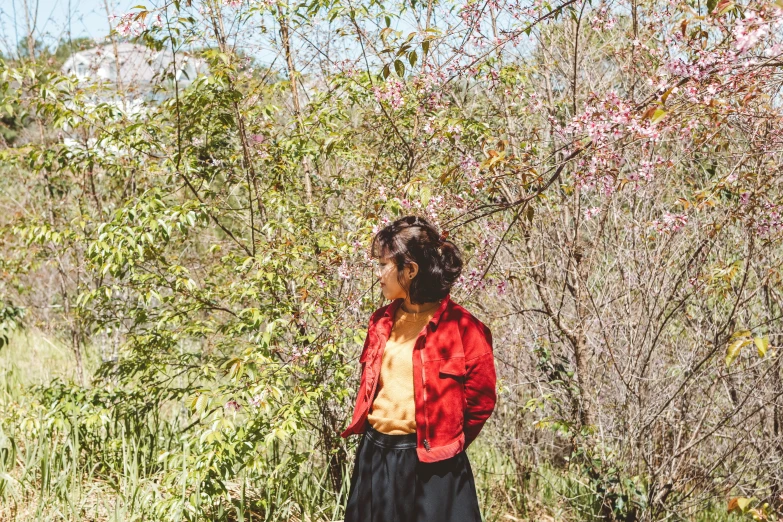 a girl standing by some bushes with flowers