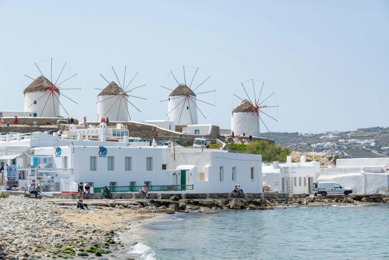 a line of three buildings and windmills near the sea