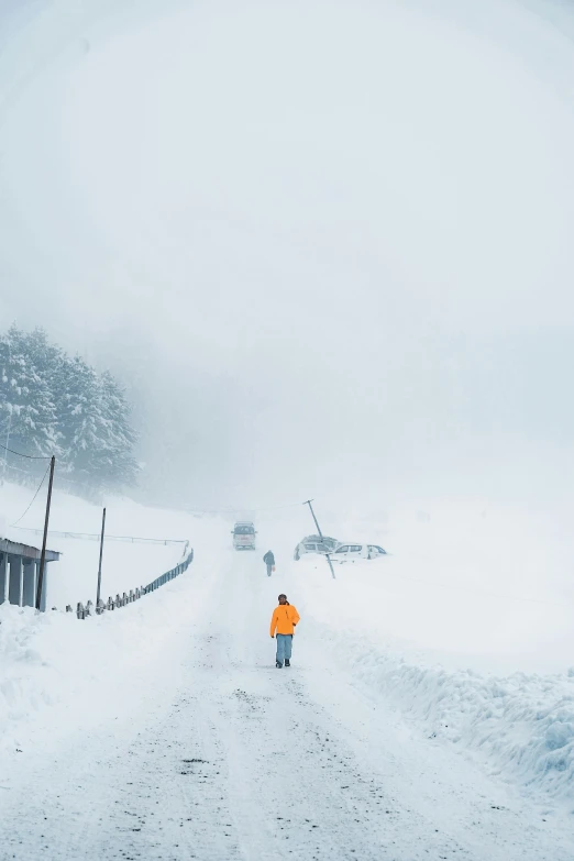 person walking on road with snow piled to the sides