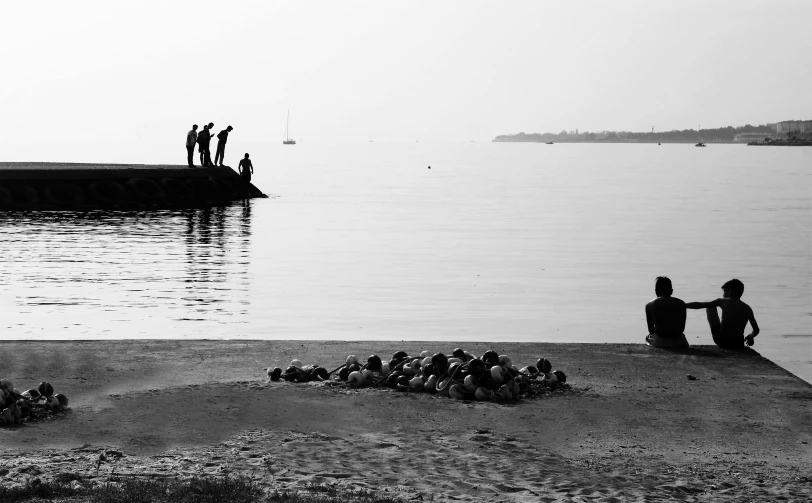 people sitting on the bank of the water near shore