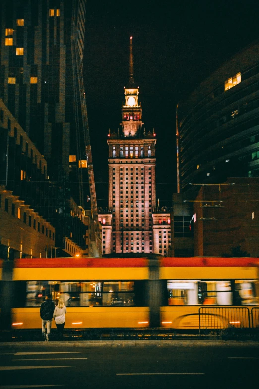 the city bus is driving past a tall building