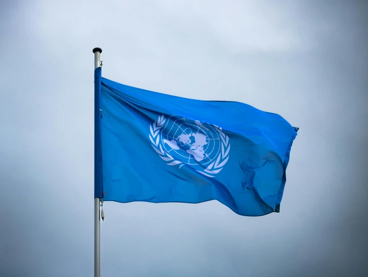 blue flag in front of a cloudy sky on the corner of the united nations flag