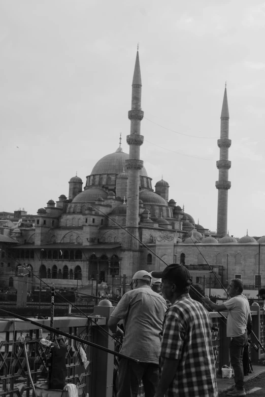 the men are standing by the railing near the mosque