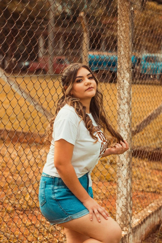 a woman leans against a fence, leaning on a metal pole