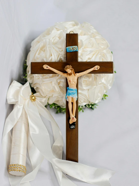 a christ crucifix with a bouquet of white roses