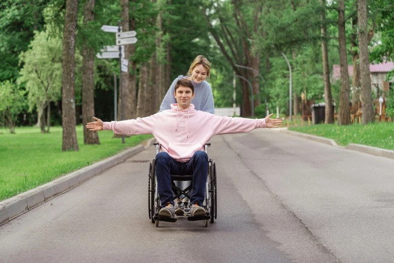 woman hing man in wheel chair on road during daytime