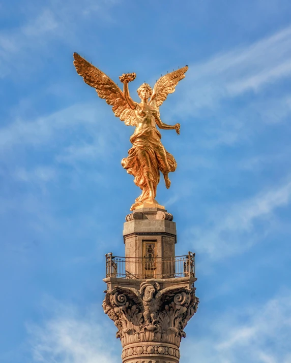 a golden statue on top of a spire on a clear day