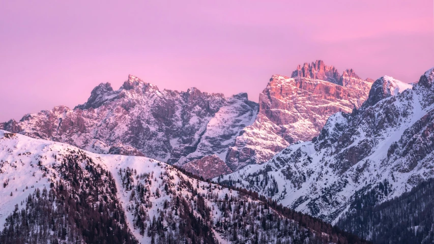 the mountains are covered in snow during sunset