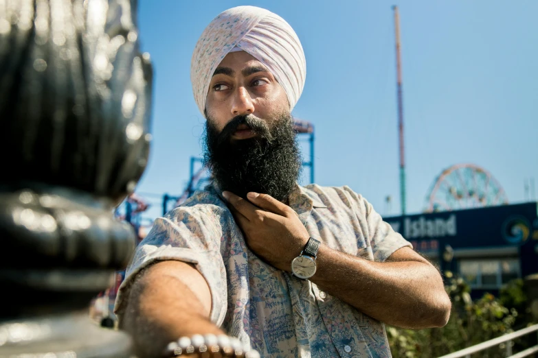 a bearded man in white turban is holding his hands in one hand and the other hand in the other hand