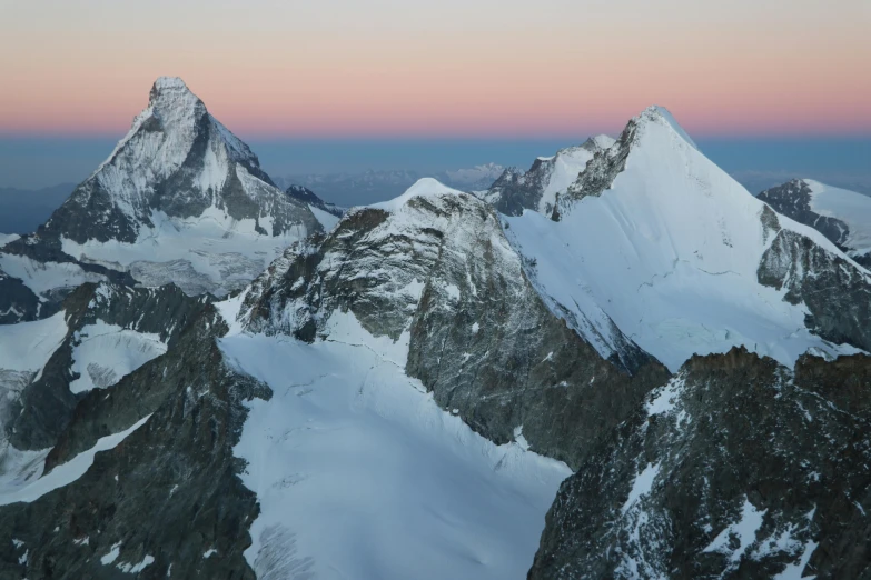 mountains covered in snow at sunrise with pink skies