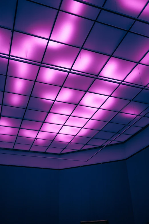 fluorescent lighting shines purple, above a room full of white couches