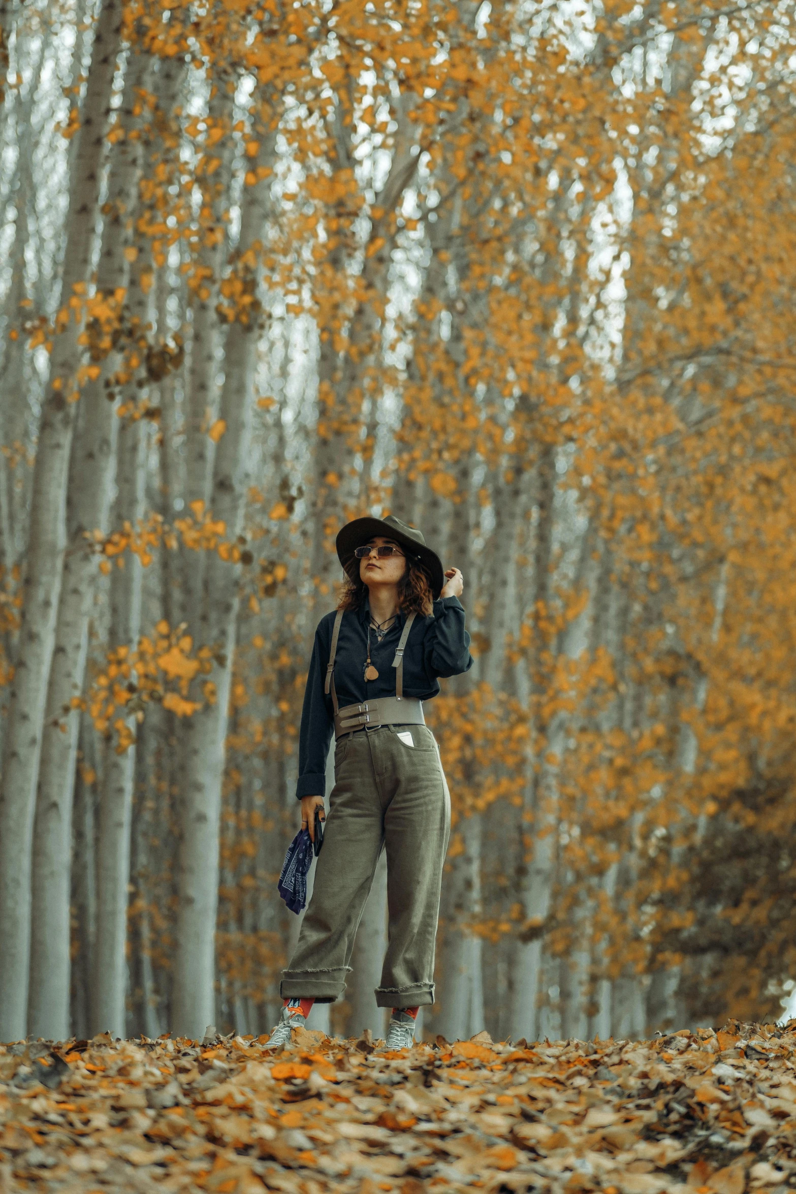 the woman standing in the woods with a hat on