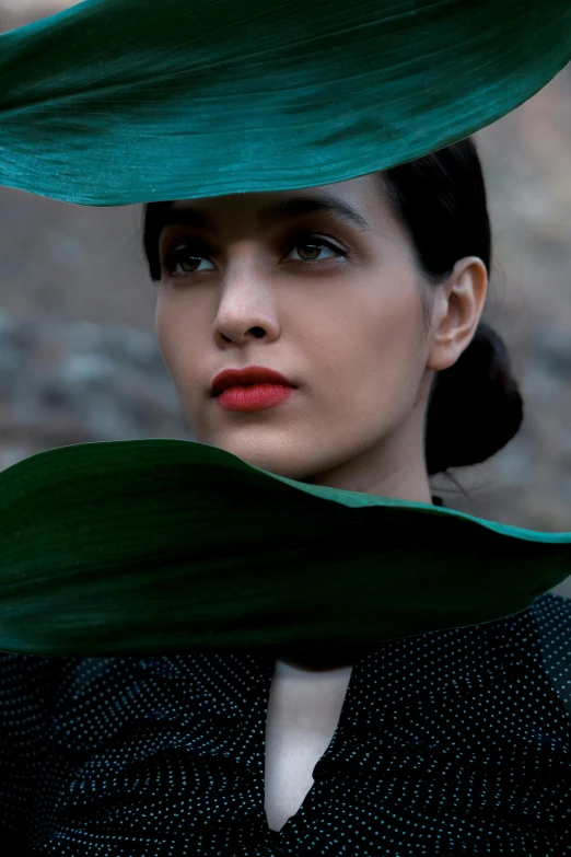 woman with dark hair and green leaves covering her head