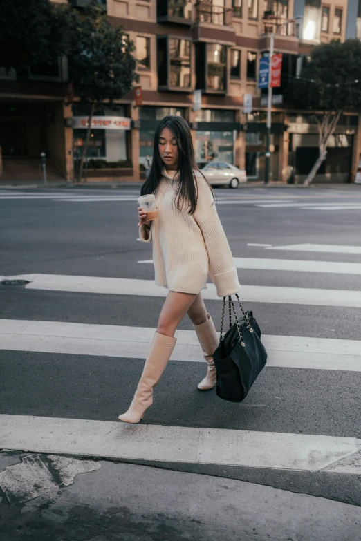 a woman in a dress is crosswalking and holding her bag