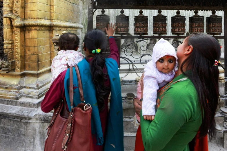 three woman and one child standing near a building