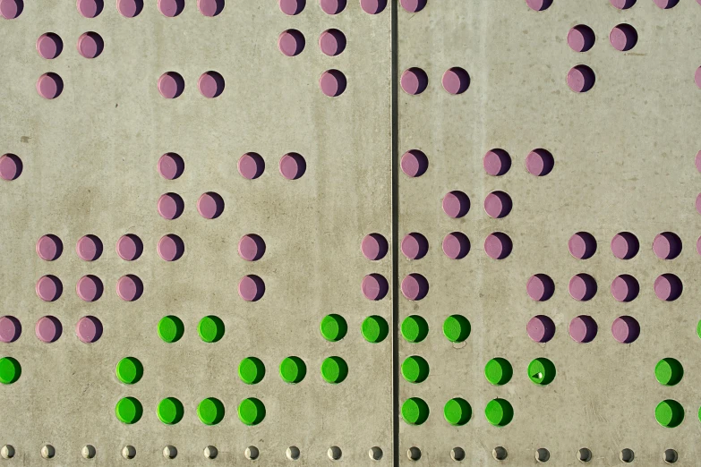 the side of a building with green and purple painted dots on it