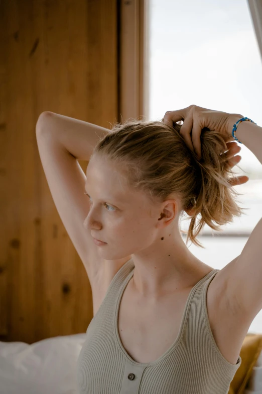 young woman straightening hair in messy styled ponytail