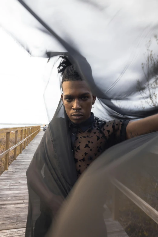 the man is wearing a gray veil next to a pier