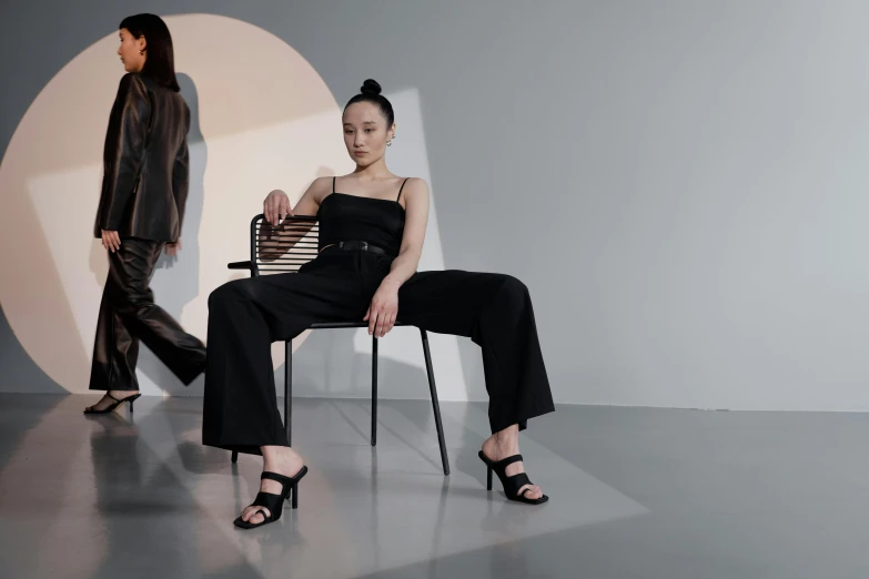 a woman in a black dress is sitting in a chair