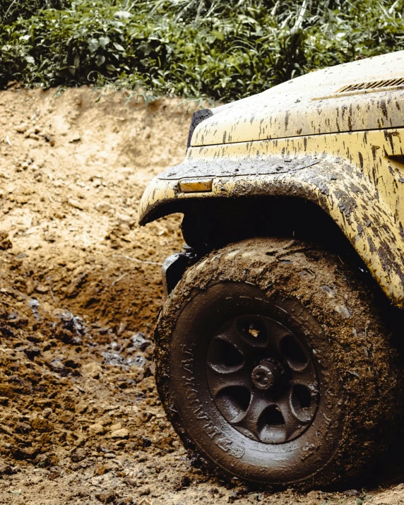 dirty yellow truck with mud off the back tire and rocks