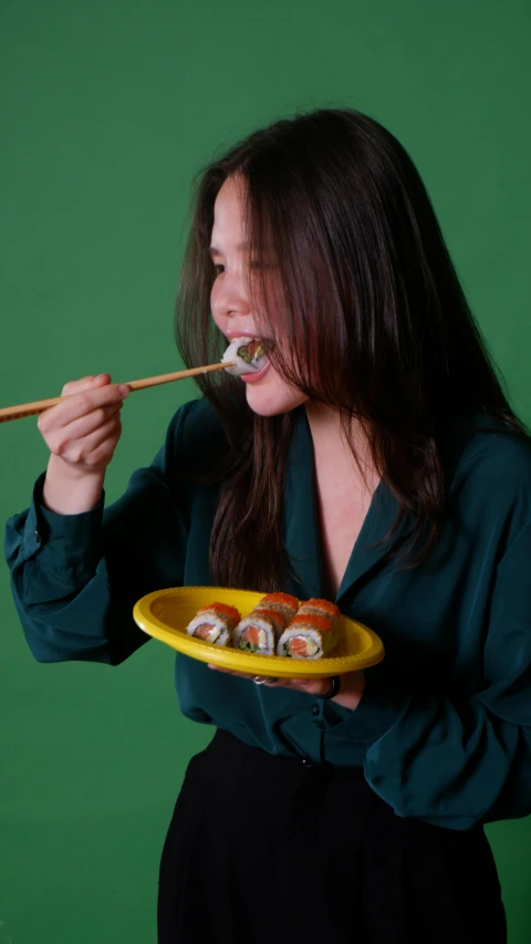 a person holding a plate and eating sushi