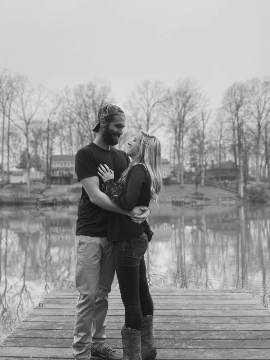 a couple kissing on the pier of a lake