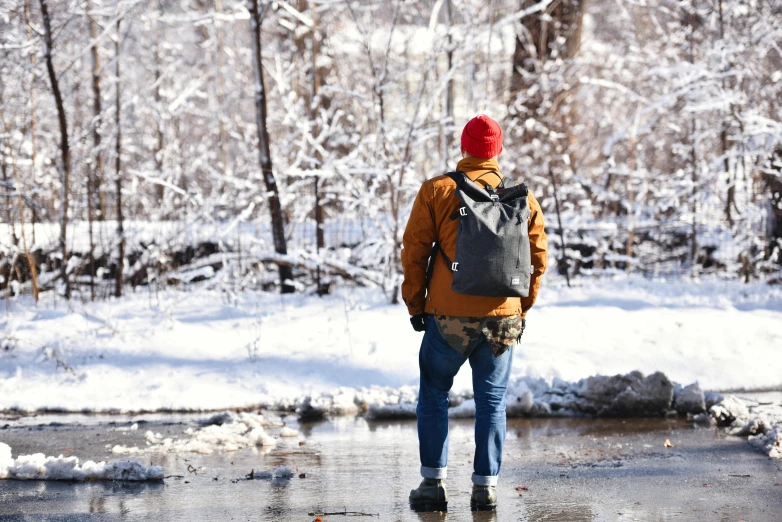 the man is wearing a backpack and walking through the frozen water