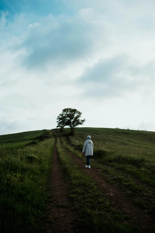 an image of a woman walking uphill with a white coat on