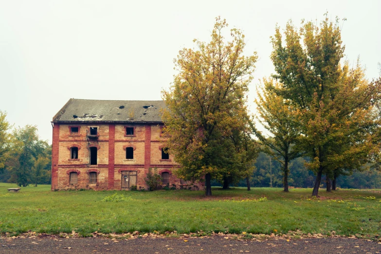 an abandoned house with two trees in front