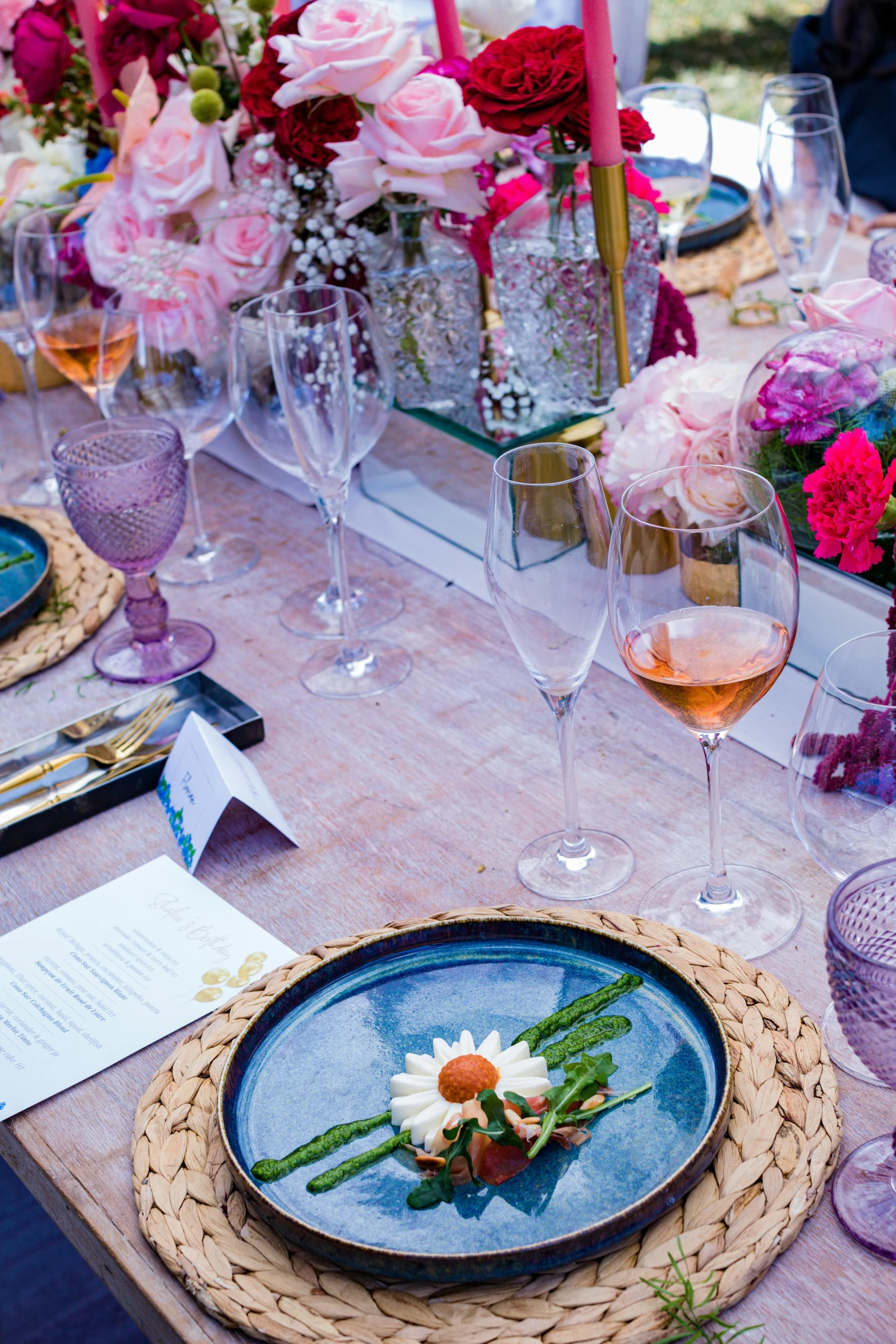 a colorful dinner table with wine and flowers