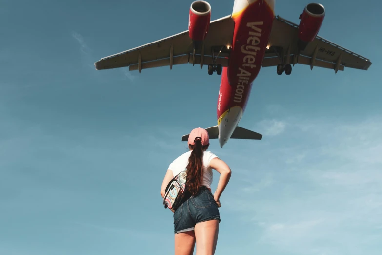 a woman looking up at a commercial jet airliner