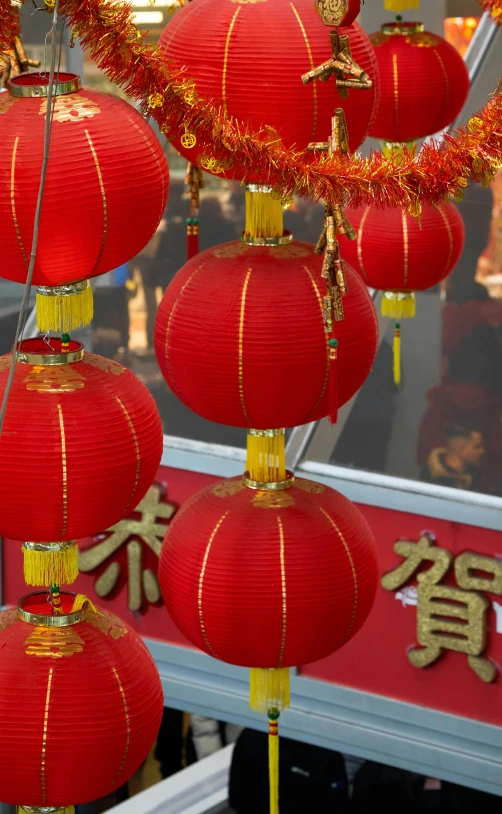 red lanterns decorated with gold string hang from a ceiling