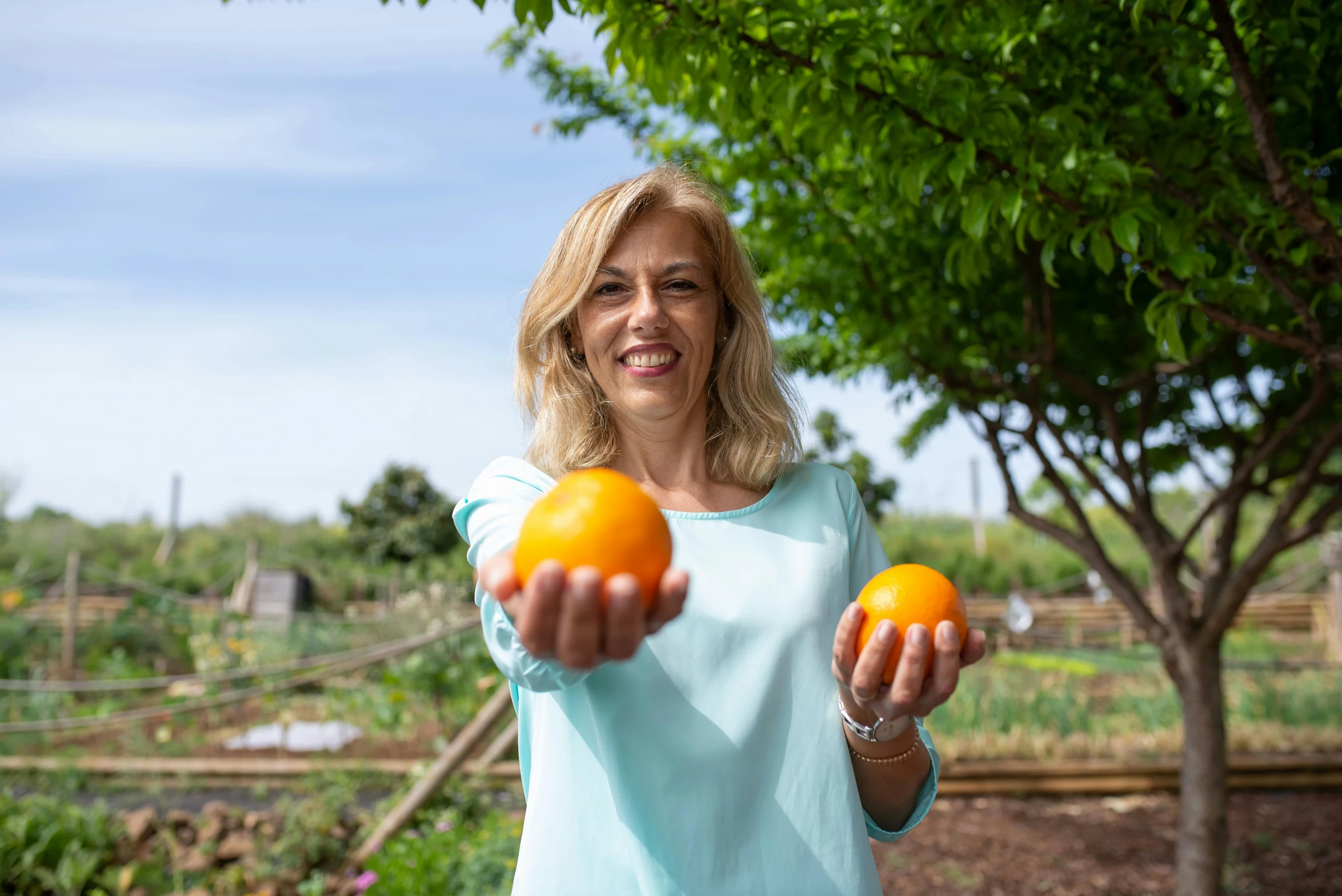 a woman holding some oranges in her hands