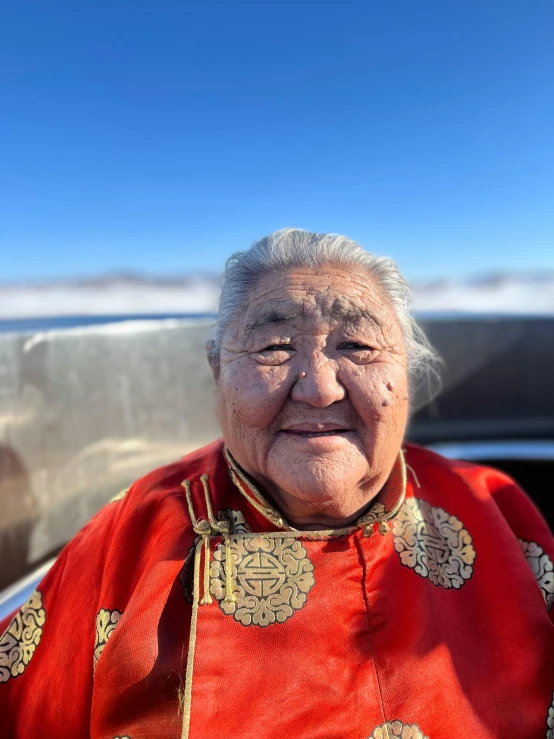 an old asian woman wearing a red jacket smiling