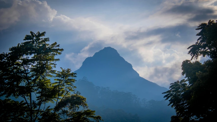 the mountain is against the cloudy sky in a forest